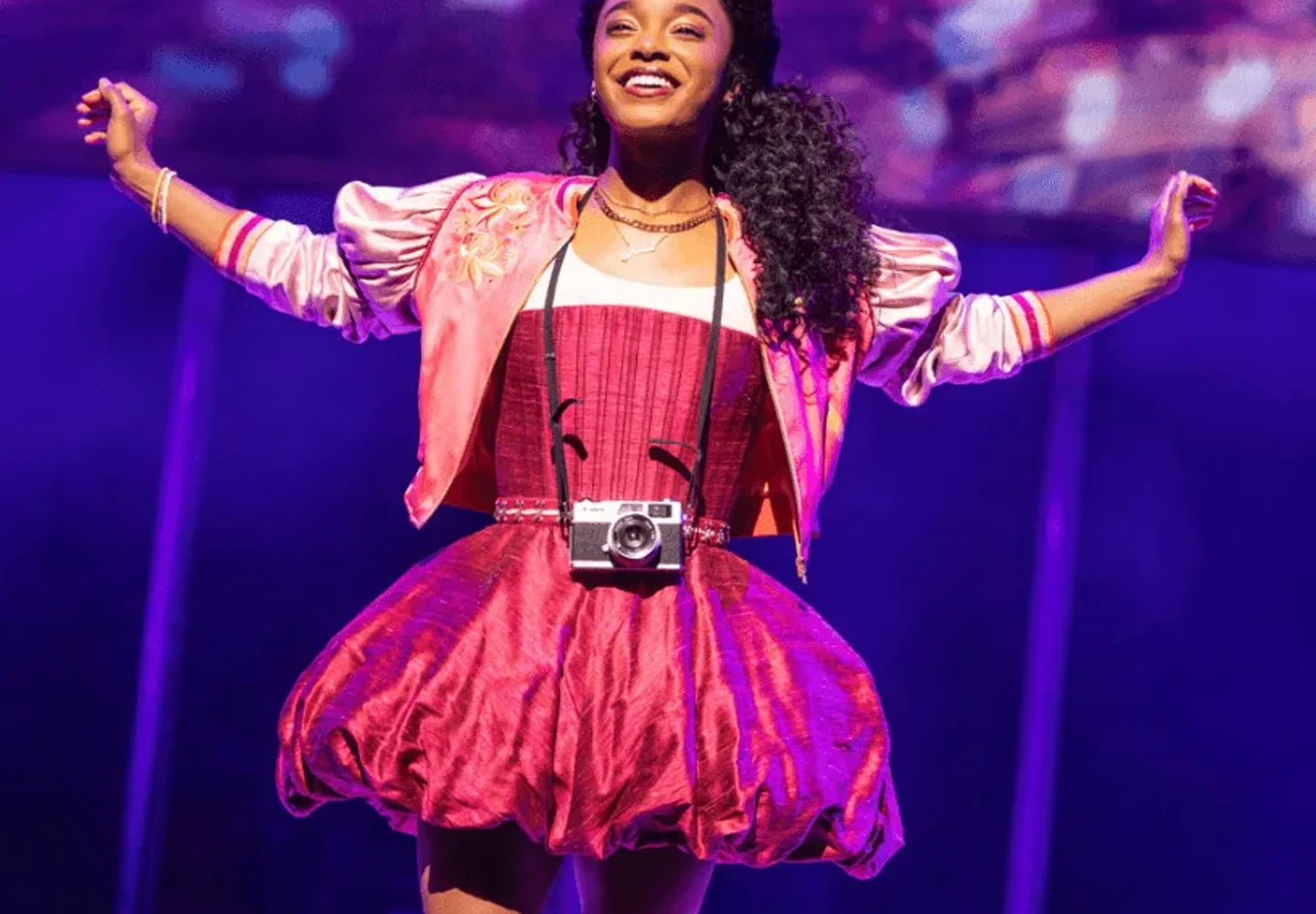 A performer in a bright pink costume on the & Juliet stage