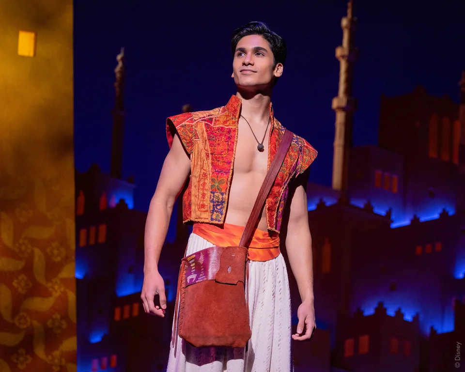 Aladdin on stage in a red waistcoat