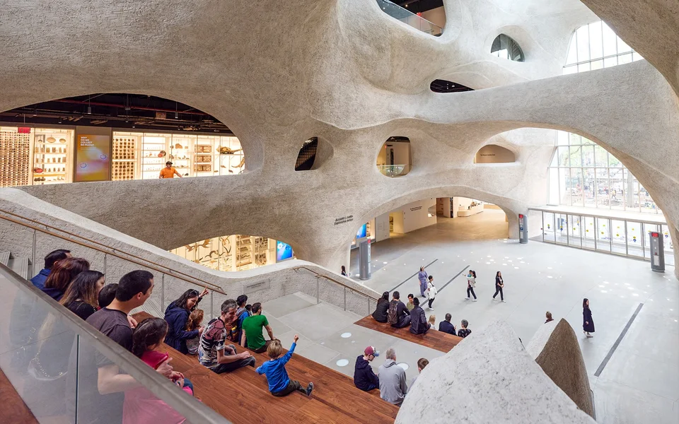 Visitors seated inside the sculpted atrium of the Gilder Center