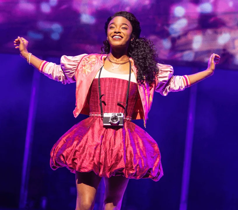 A performer in a bright pink costume on the & Juliet stage