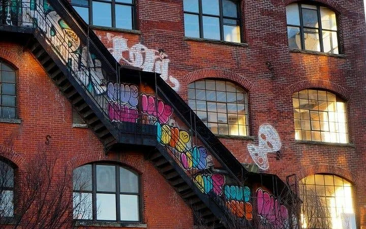 Graffiti und eine Metalltreppe an einem Backsteingebäude
