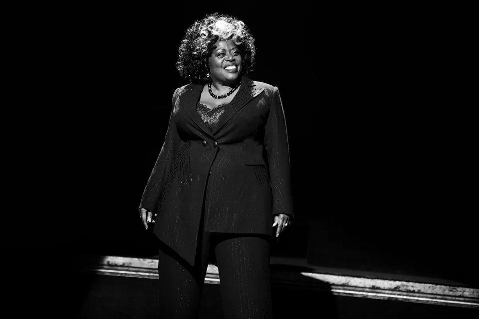 Chicago performer in a black suit under a spotlight