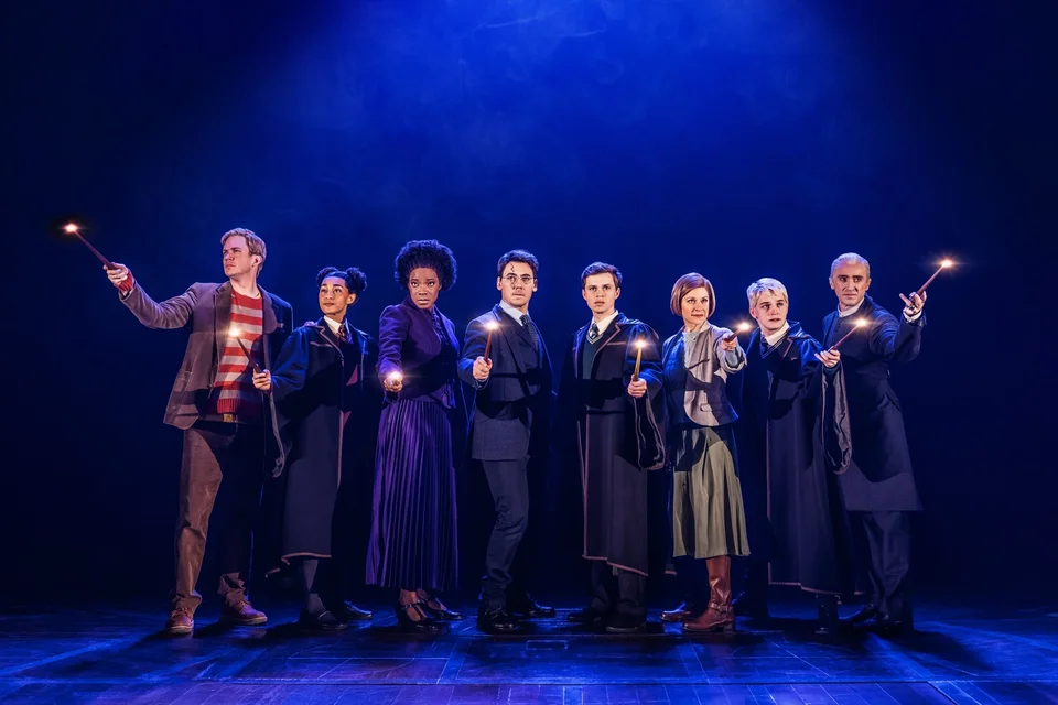 The Harry Potter and the Cursed Child ensemble holding wands under blue lighting