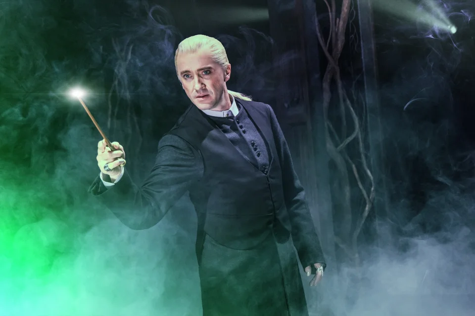 A Harry Potter and the Cursed Child performer holding a wand in green mist