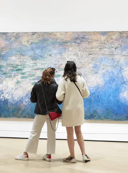 Two visitors studying a large blue painting at MoMA