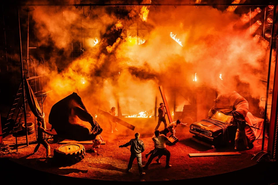 A dramatic scene from The Outsiders under orange stage lighting