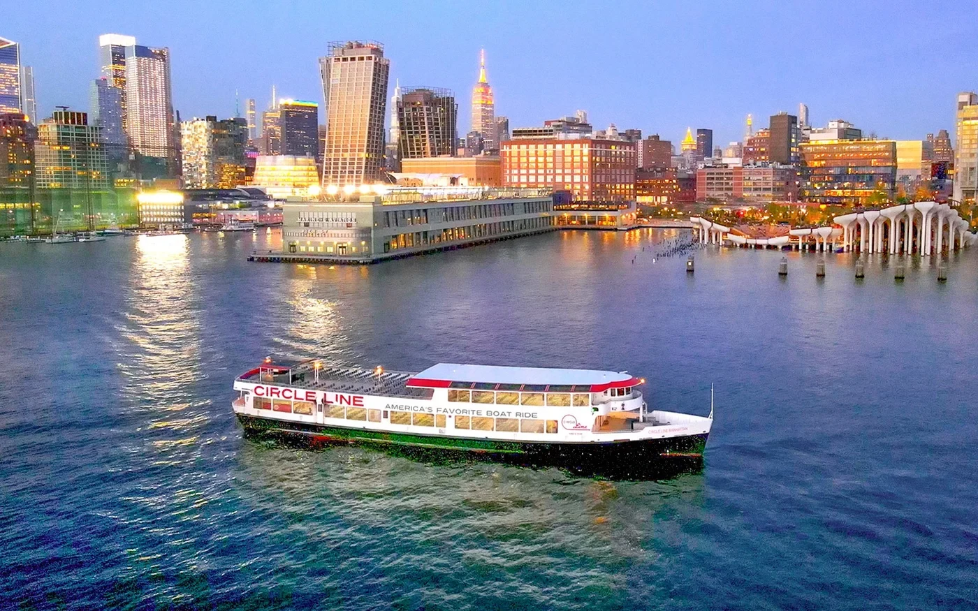 Illuminated sightseeing boat on New York Harbor at dusk
