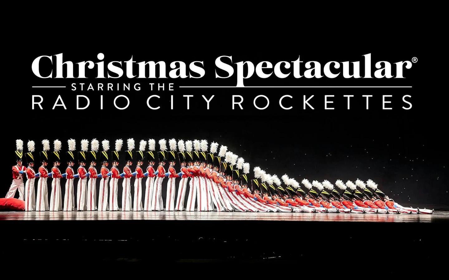 The Radio City Rockettes Christmas Spectacular title above a line of dancers on stage